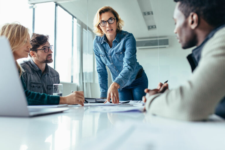 Une Femme manager discute avec ses 3 collaborateurs sur un projet en cours
