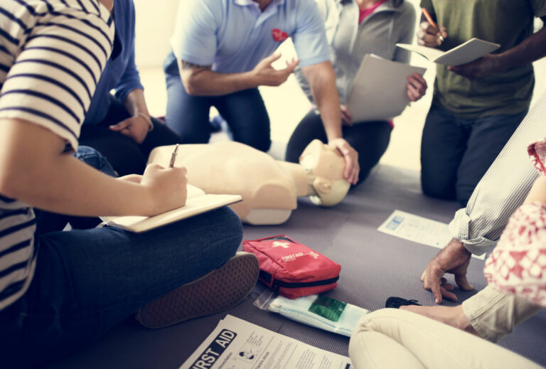 Cours de secourisme: une personne montre les gestes de premiers secours à un groupe de stagiaires.